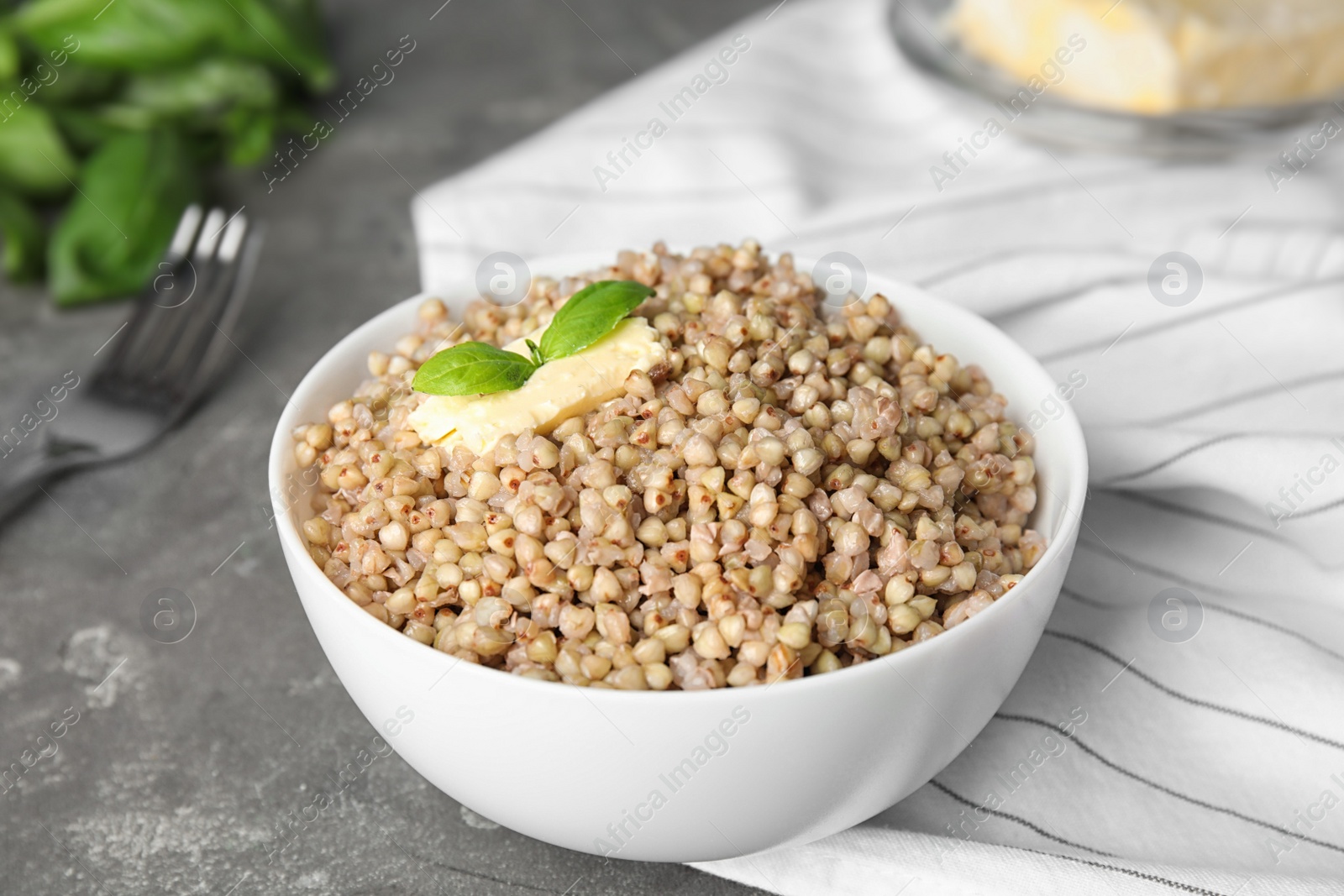 Photo of Tasty buckwheat porridge with butter on grey table