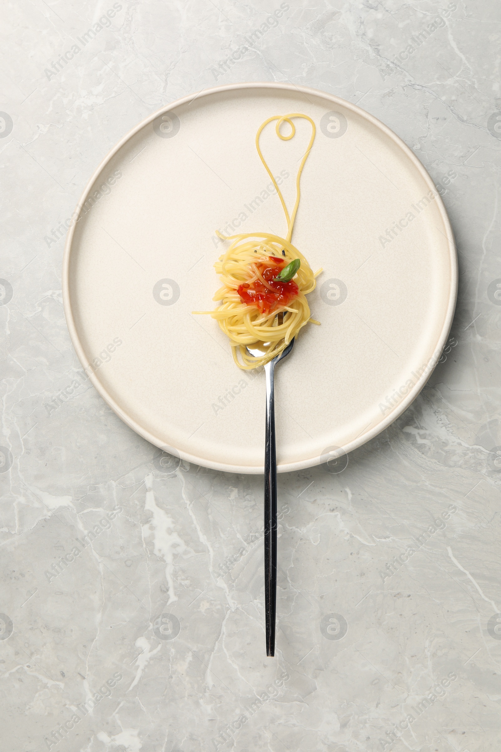 Photo of Heart made with spaghetti and fork on grey table, top view