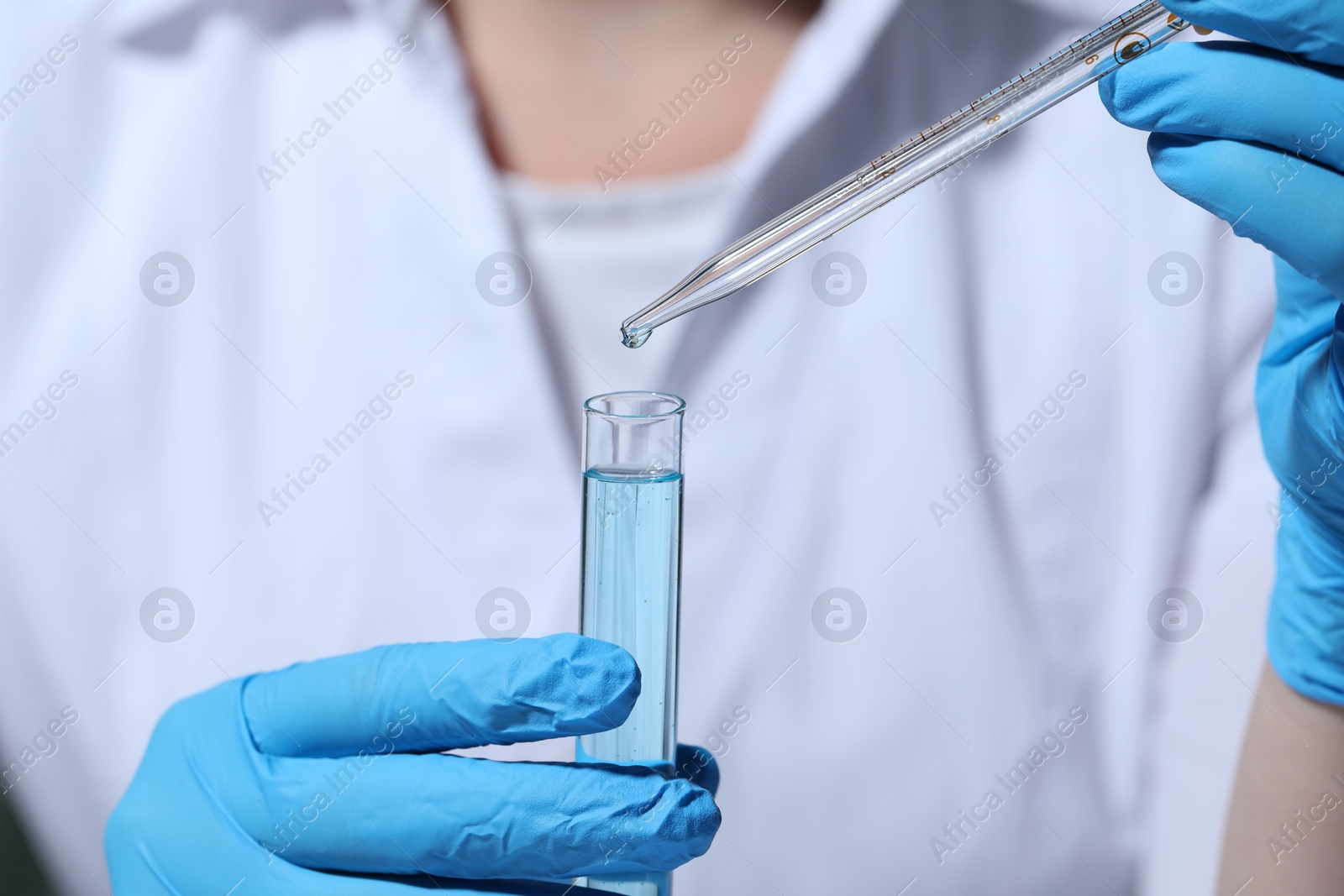 Photo of Scientist dripping liquid from pipette into test tube, selective focus