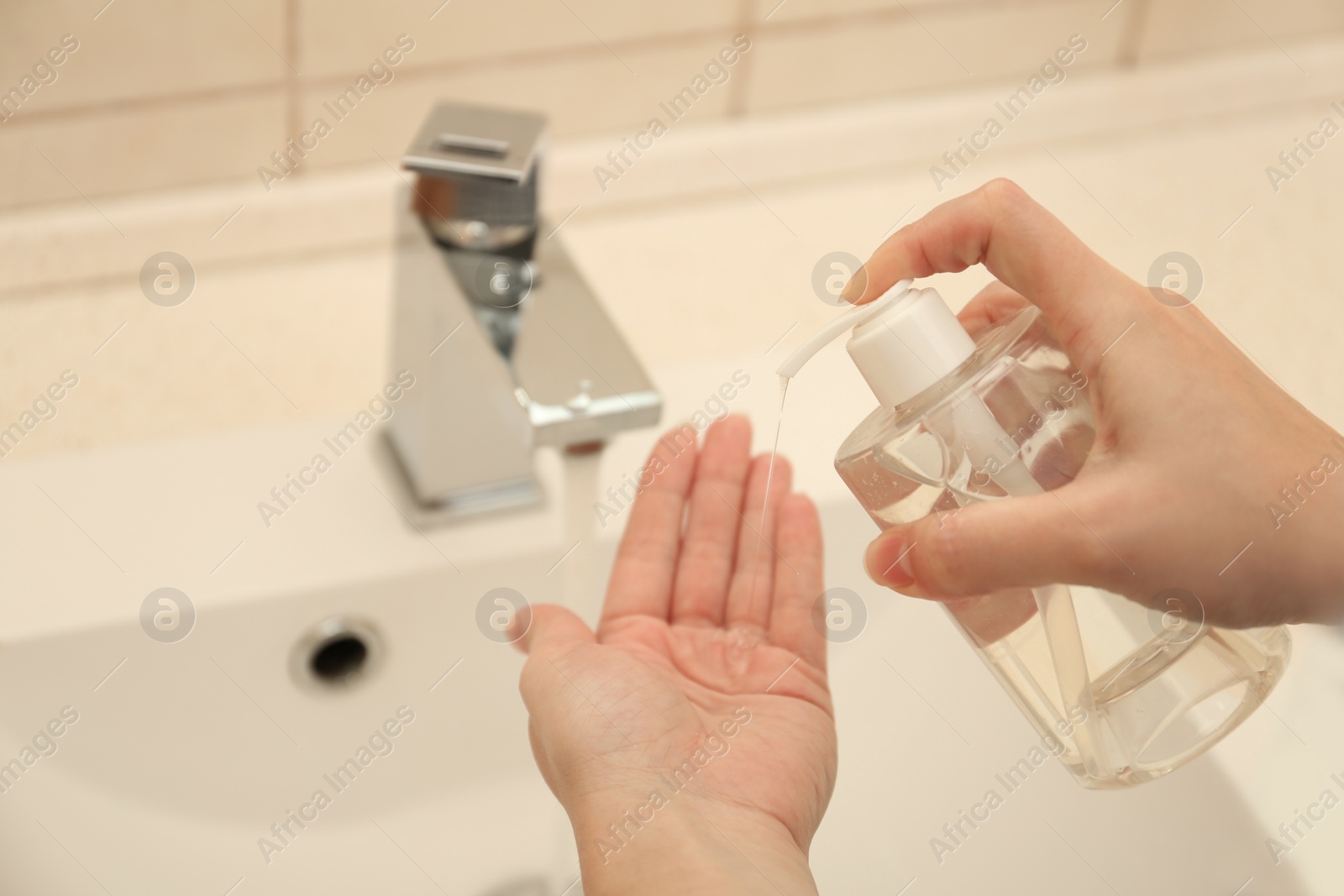 Photo of Woman applying antiseptic soap onto hand in bathroom, closeup. Virus prevention