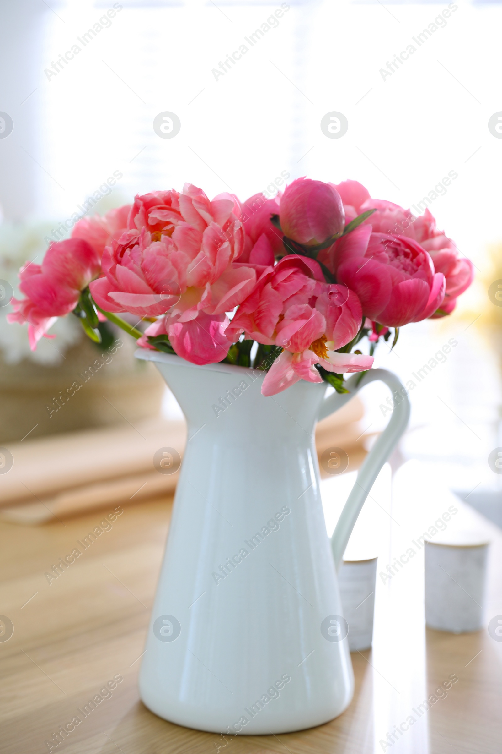 Photo of Beautiful bouquet of fragrant peonies in vase on table indoors