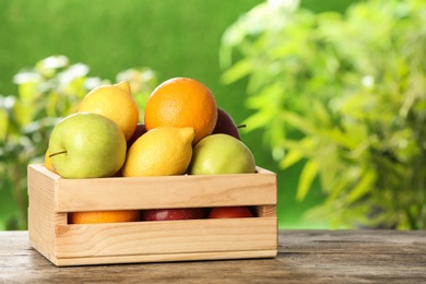 Photo of Wooden crate with fresh ripe fruits on table outdoors, space for text