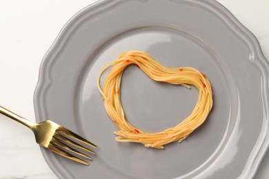Photo of Heart made with spaghetti and fork on white table, top view