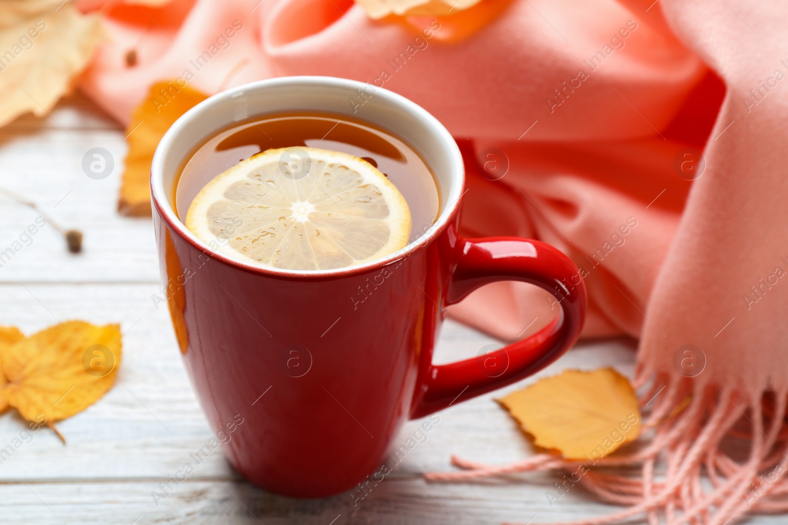 Photo of Cup of hot drink and leaves on white wooden table. Cozy autumn atmosphere