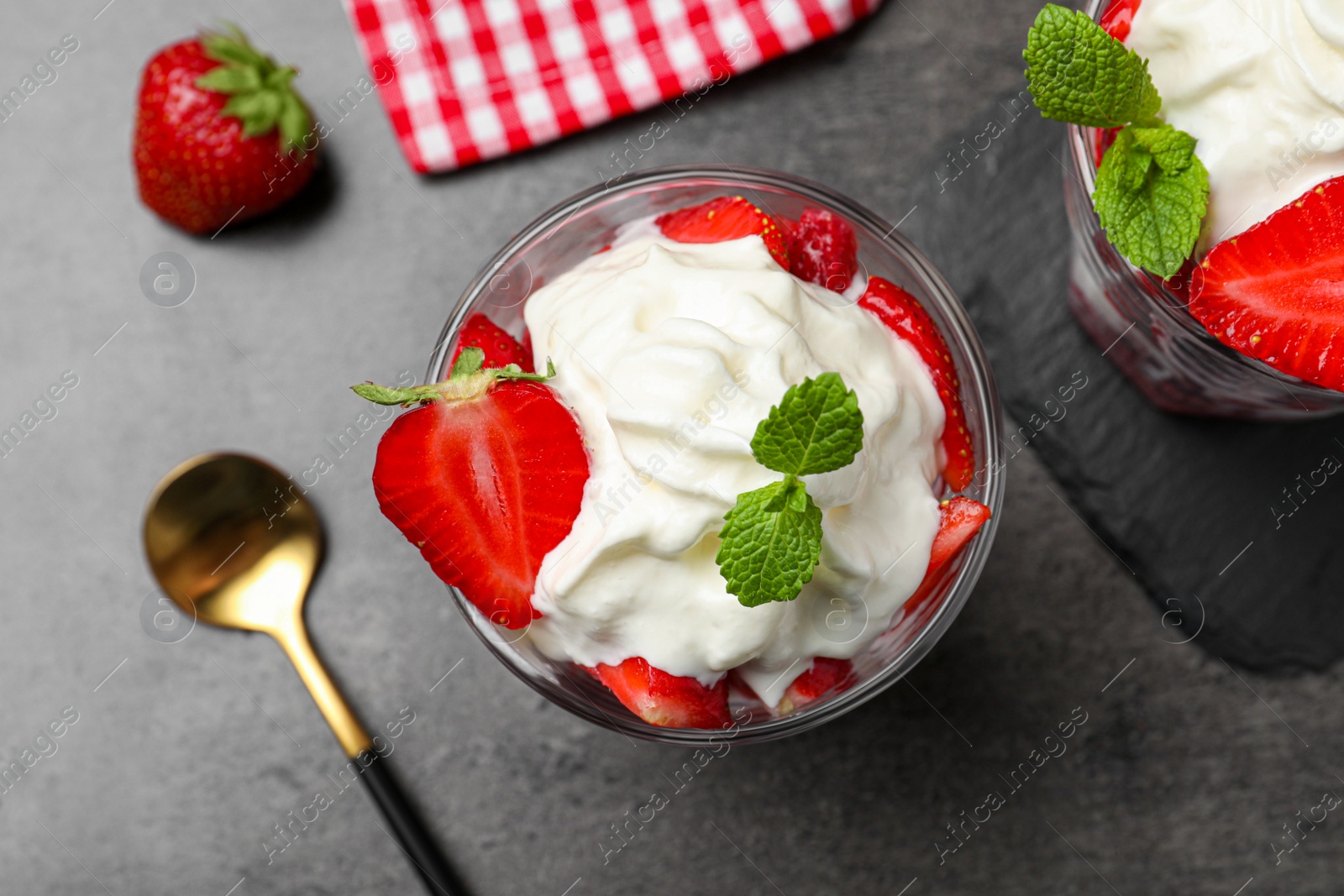 Photo of Delicious strawberries with whipped cream served on grey table, flat lay