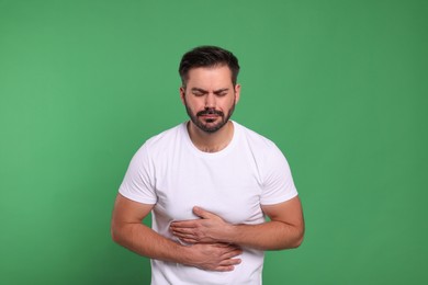 Photo of Unhappy man suffering from stomach pain on green background