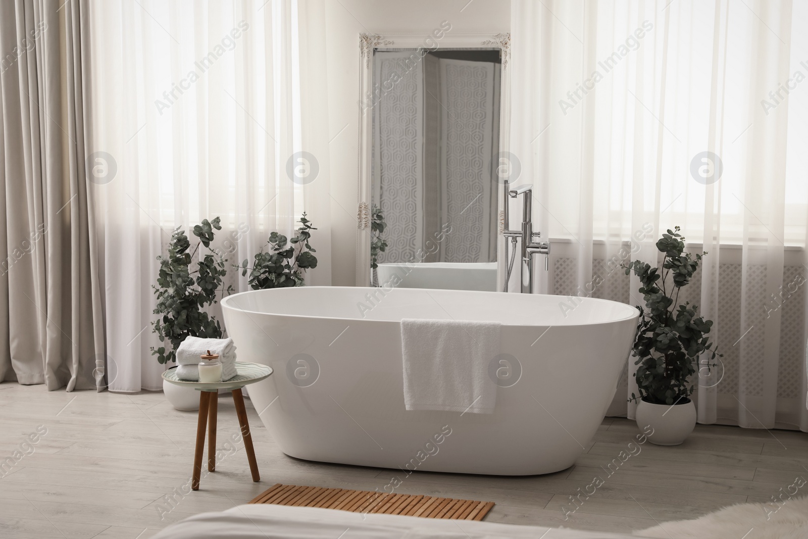 Photo of White tub and decor in light room. Interior design