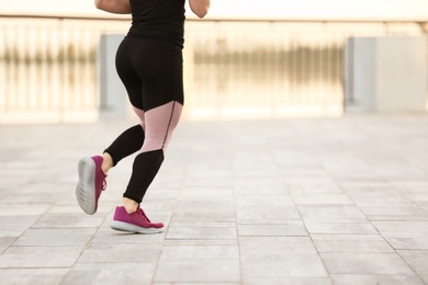 Photo of Young woman running outdoors on sunny day