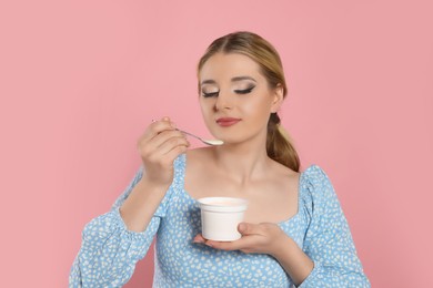 Photo of Woman eating tasty yogurt on pink background
