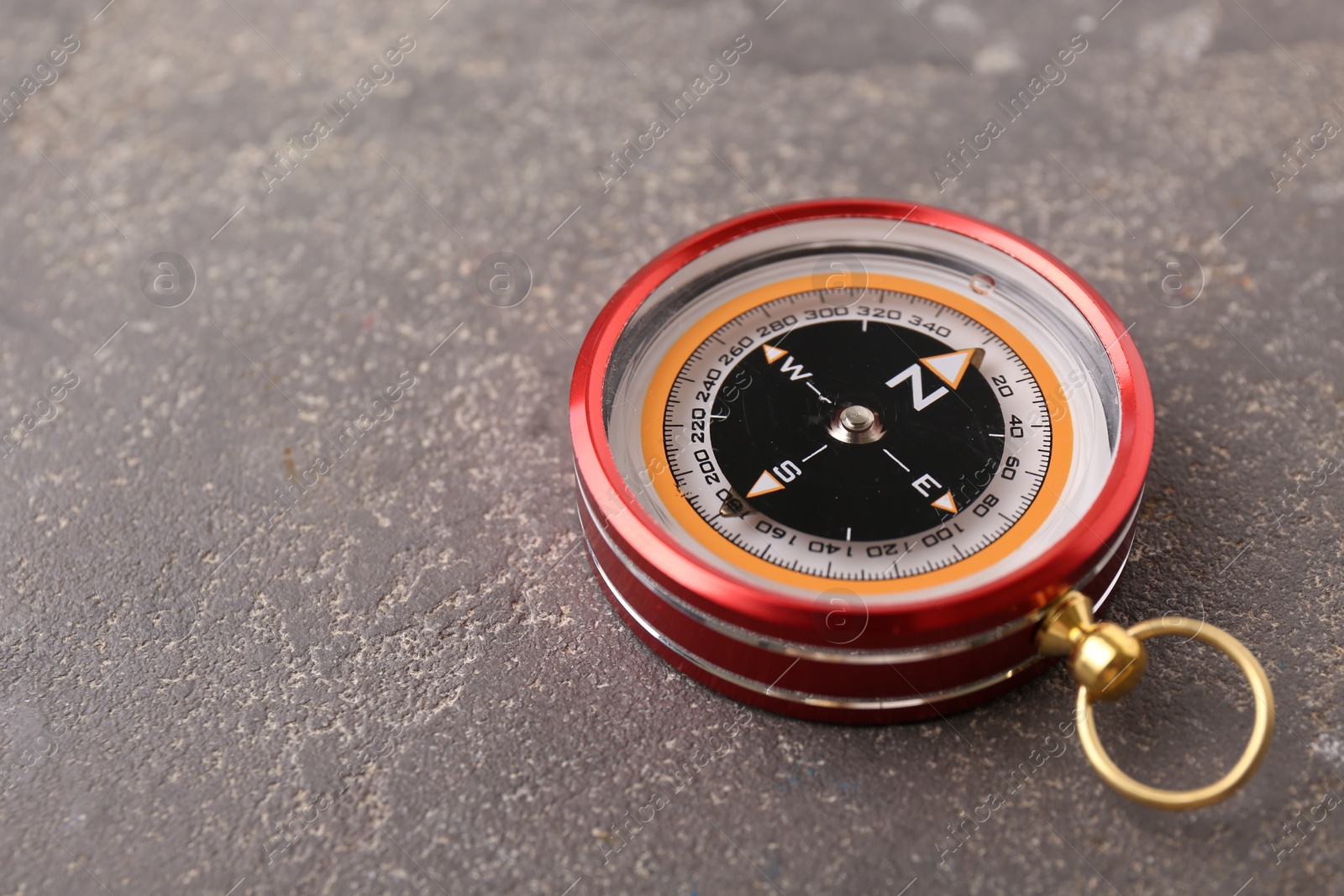 Photo of One compass on grey textured background, closeup. Space for text