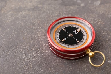 Photo of One compass on grey textured background, closeup. Space for text