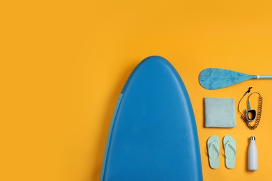 Photo of Flat lay composition with SUP board on yellow background, space for text. Water sport