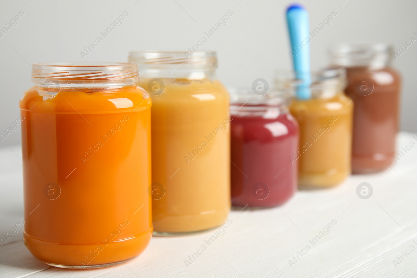 Photo of Healthy baby food in jars on white wooden table