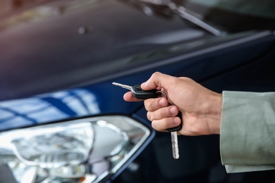 Man with car keys near new auto, closeup