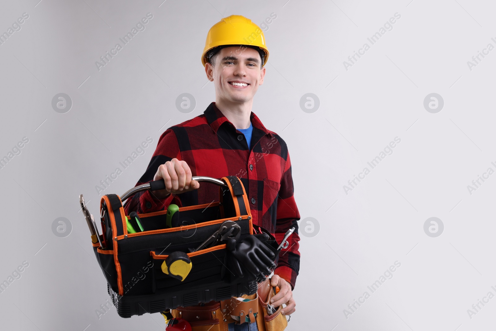 Photo of Professional repairman with tool box on light grey background. Space for text