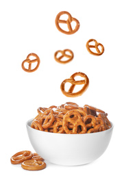 Image of Tasty crispy pretzel crackers falling into bowl on white background
