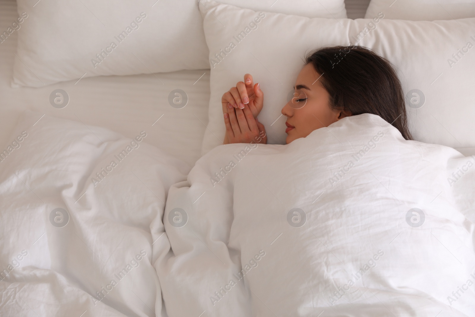 Photo of Young woman covered with warm white blanket sleeping in bed, top view. Space for text