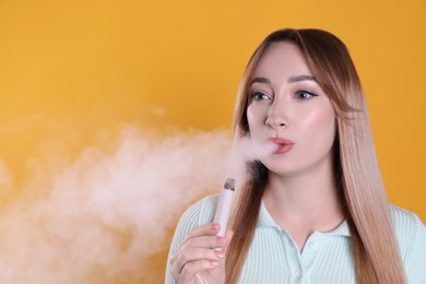 Young woman using electronic cigarette on orange background