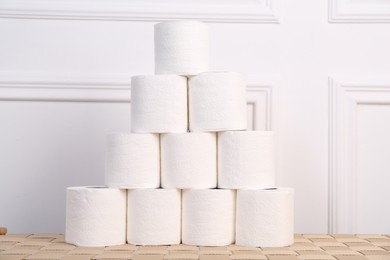 Photo of Pyramid of toilet paper rolls on wicker table