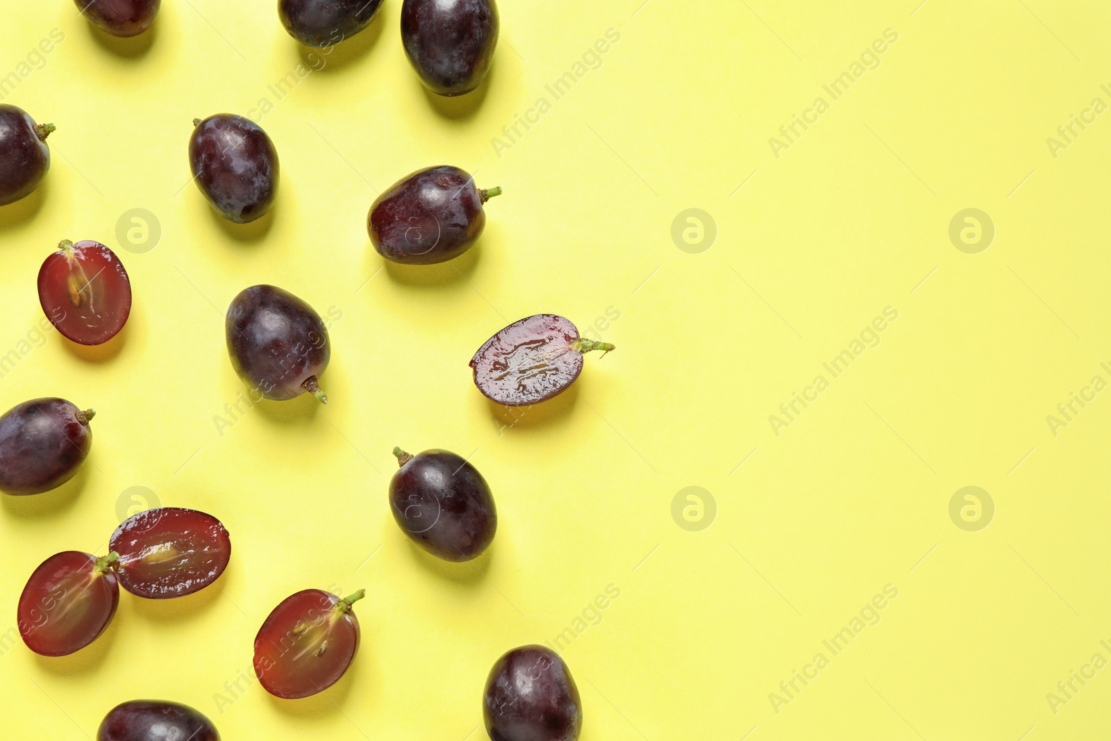Photo of Flat lay composition with fresh ripe juicy grapes on yellow background, space for text