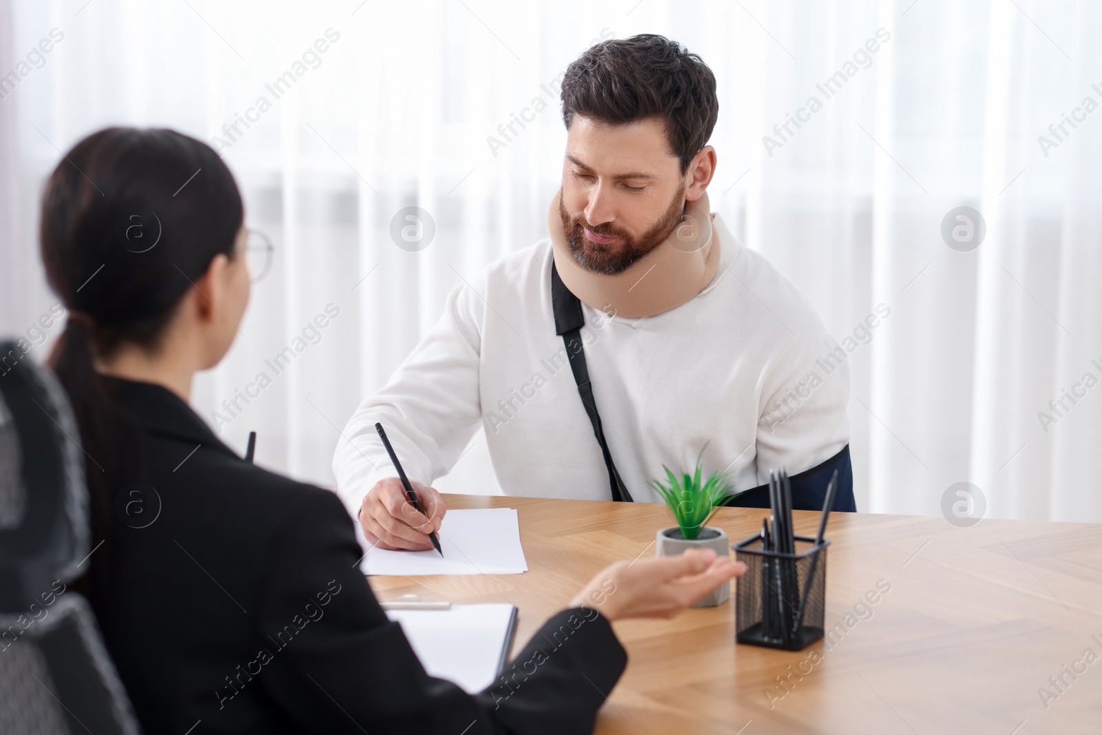 Photo of Injured man signing document in lawyer's office, selective focus