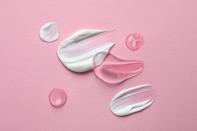 Samples of transparent gel and white cream on pink background, flat lay