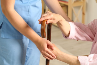 Photo of Elderly woman with walking cane and female caregiver indoors, closeup