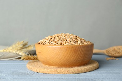 Photo of Bowl with wheat grains on pale light blue wooden table