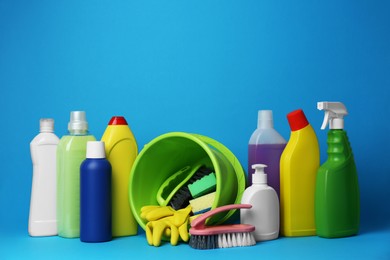 Photo of Green bucket, cleaning supplies and tools on light blue background