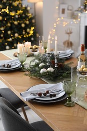 Christmas table setting with festive decor and dishware in room