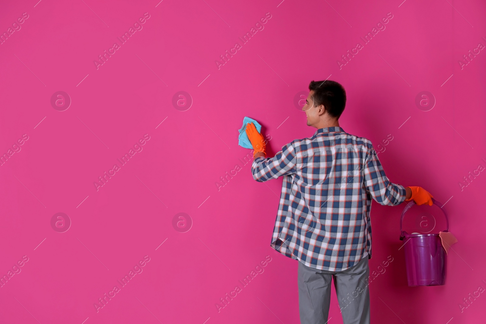 Photo of Man in gloves cleaning color wall with rag