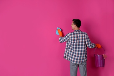 Man in gloves cleaning color wall with rag