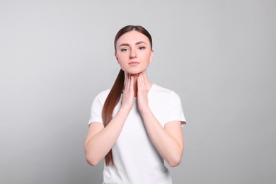 Photo of Young woman with sore throat on light grey background