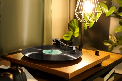 Photo of Stylish turntable with vinyl record on table indoors