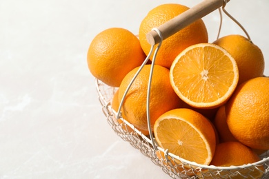 Basket with ripe oranges on light background. Space for text