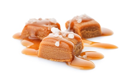 Photo of Delicious candies with caramel sauce and salt on white background