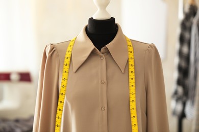 Photo of Mannequin with shirt and measuring tape in tailor shop