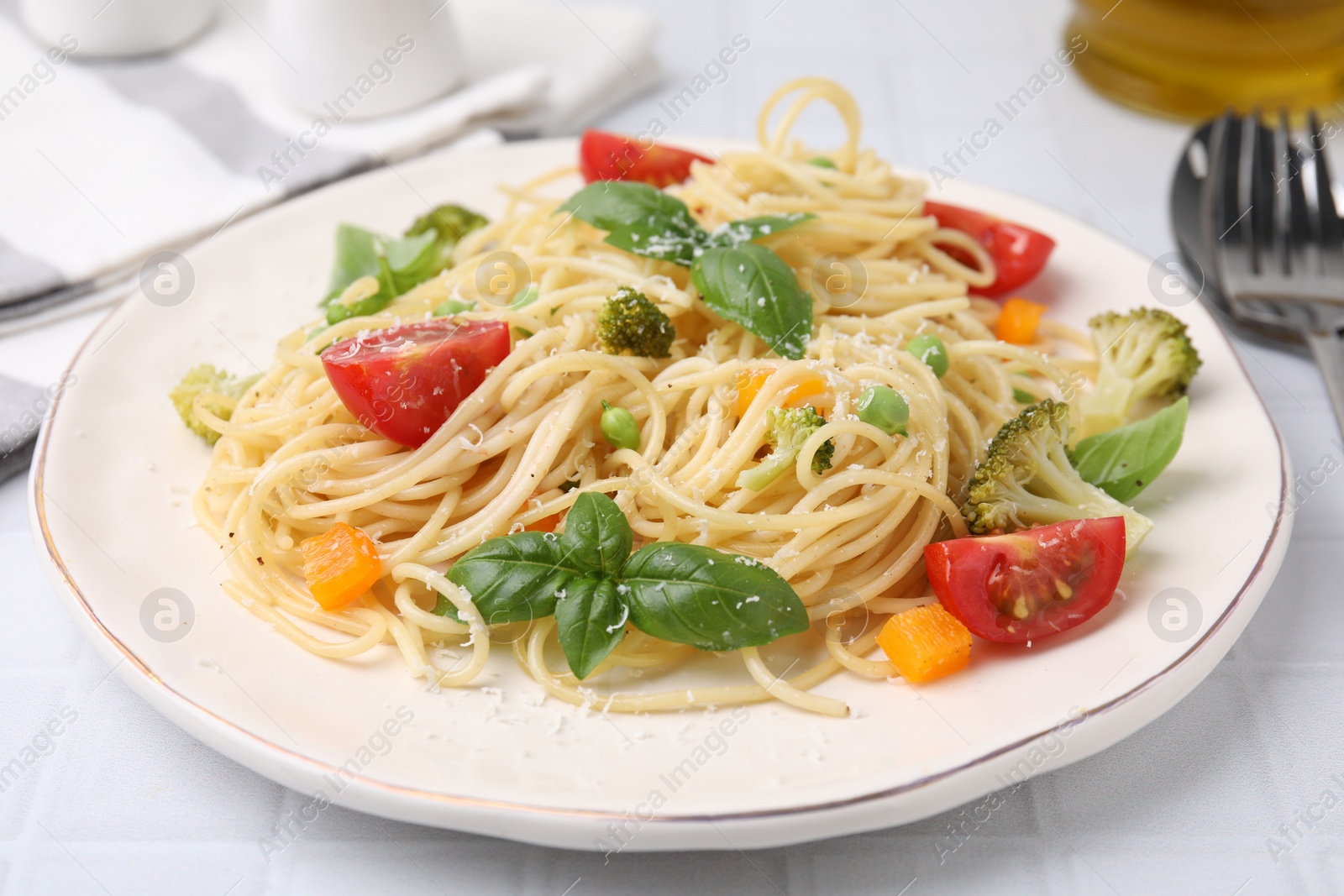 Photo of Delicious pasta primavera with tomatoes, basil and broccoli on white table, closeup