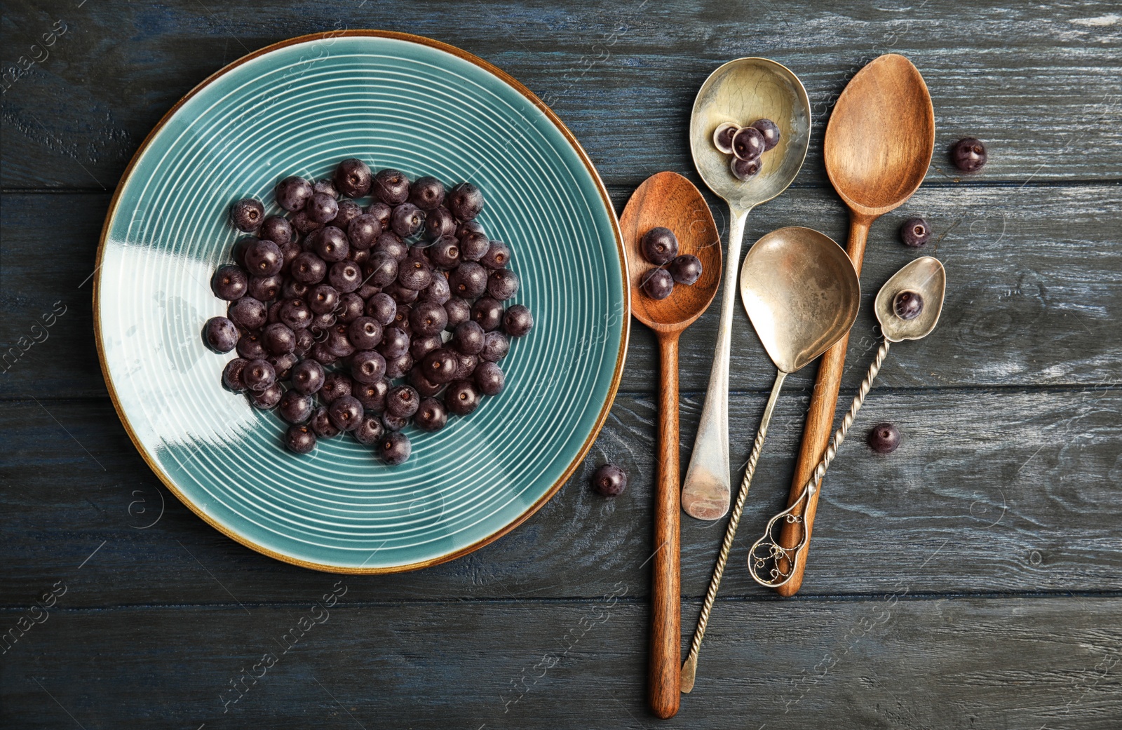 Photo of Plate with fresh acai berries and spoons on wooden table, top view