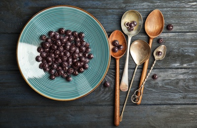 Photo of Plate with fresh acai berries and spoons on wooden table, top view