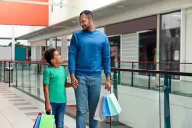 Photo of Family shopping. Happy father and son with colorful bags in mall