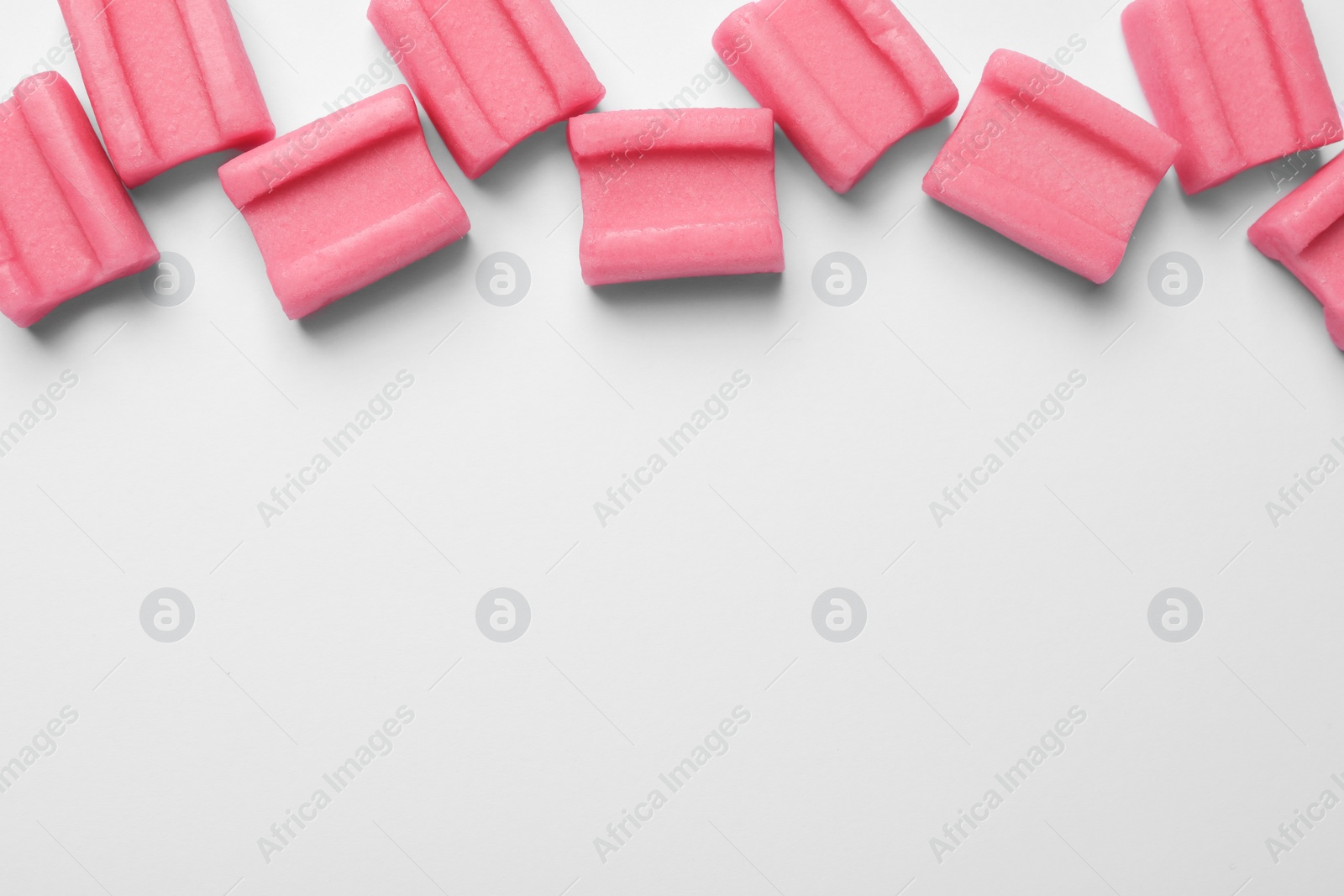 Photo of Tasty pink chewing gums on white background, flat lay. Space for text