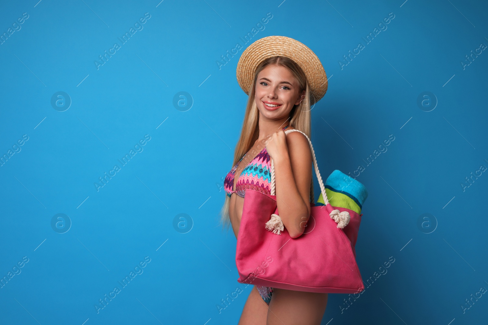 Photo of Pretty young woman wearing stylish bikini with bag on blue background. Space for text