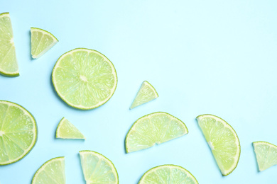 Photo of Juicy fresh lime slices on light blue background, flat lay. Space for text