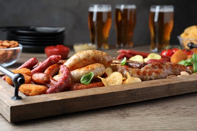 Photo of Set of different tasty snacks and beer on wooden table, closeup view