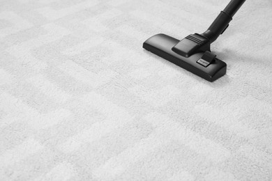 Photo of Removing dirt from white carpet with modern vacuum cleaner. Space for text