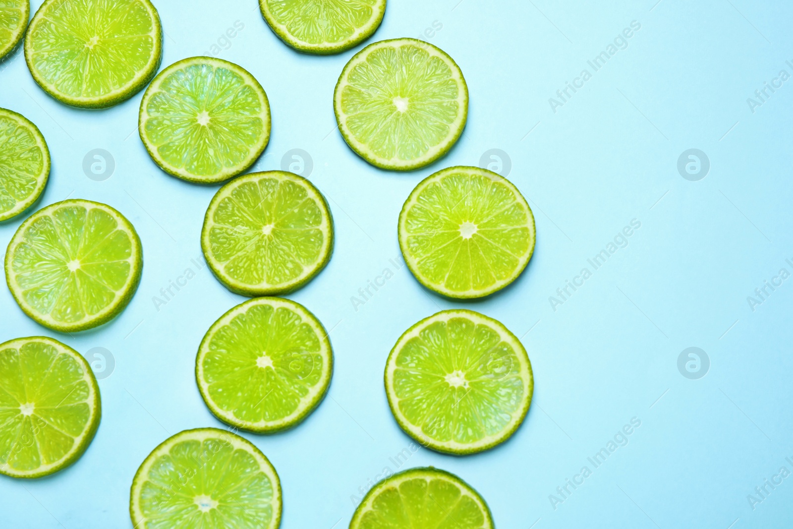 Photo of Juicy fresh lime slices on light blue background, flat lay