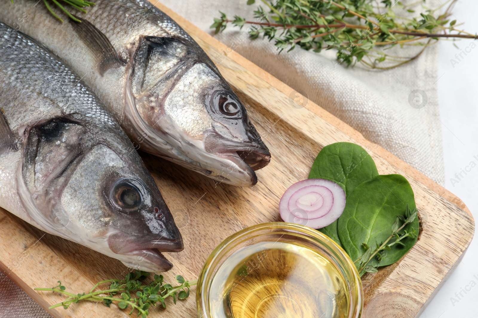 Photo of Tasty sea bass fish and ingredients on white table