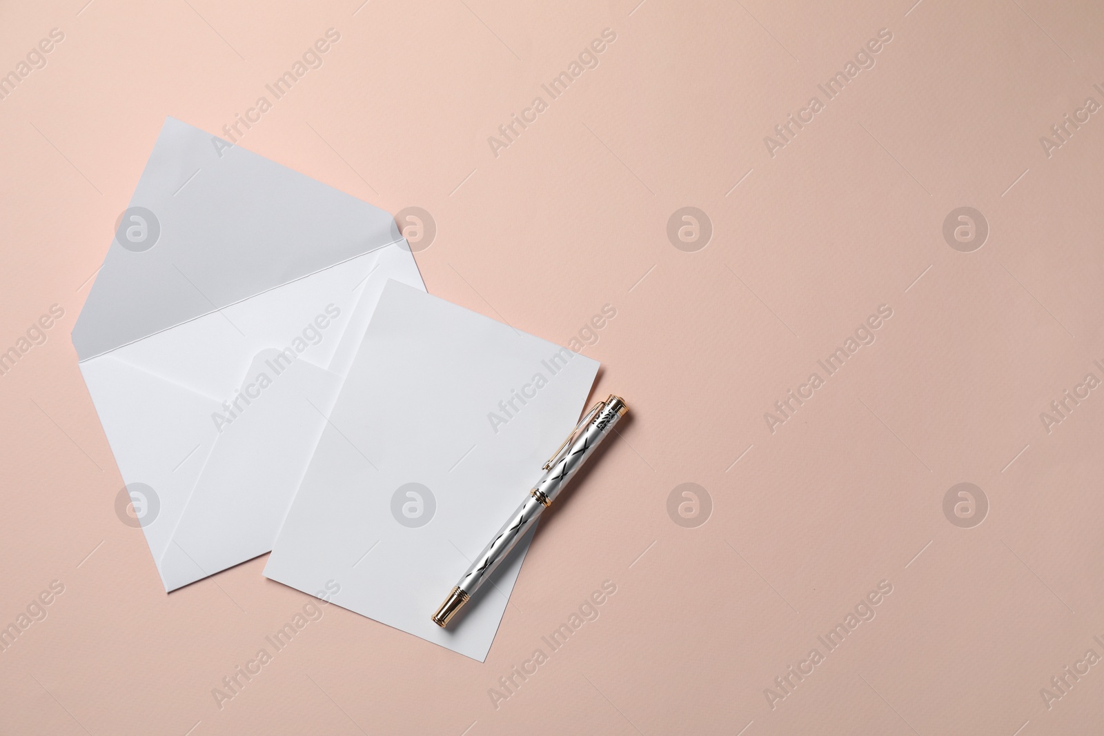 Photo of Blank sheet of paper, letter envelope and pen on beige background, top view. Space for text