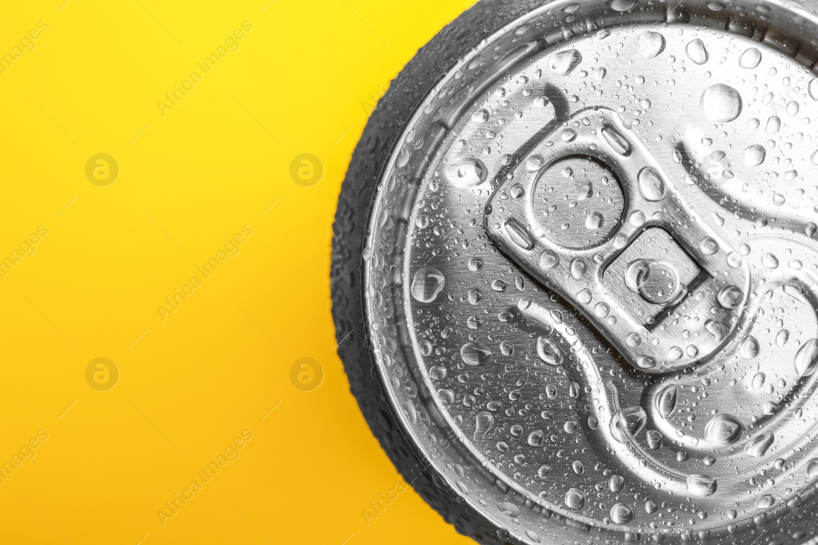 Photo of Wet closed can on yellow background, closeup. Space for text